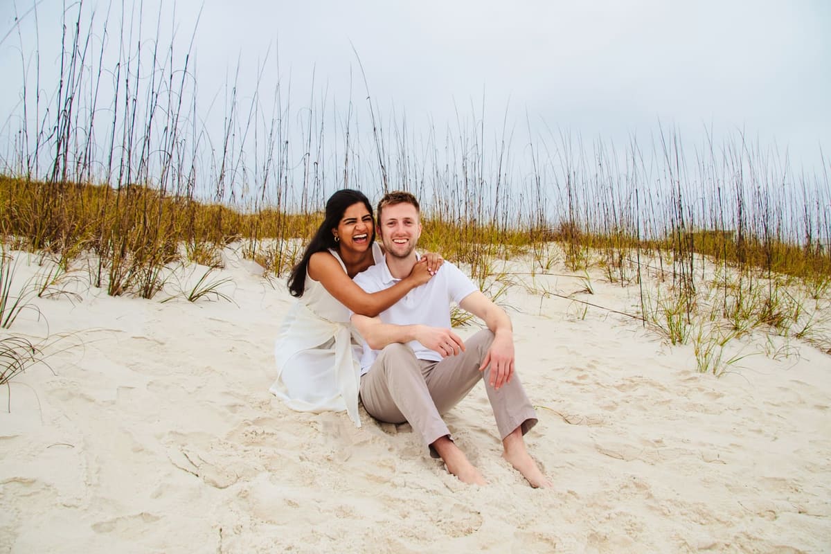 The two people behind Peristyle sitting close together on a beach, her leaning into his shoulder.